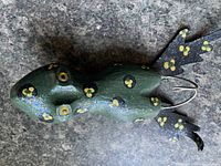 Top view of green glittered wooden frog lure with spots and metal hook