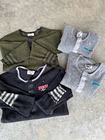 All four henley shirts laid out folded showing colors and logos