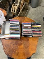 Two stacks of approximately 50 CD jewel cases, one stack inside metal tin
