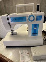 Front view of White Domestic Deluxe sewing machine with blue graphics and foot pedal