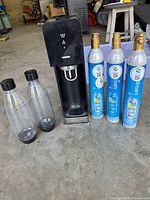 Front view of SodaStream machine, two bottles, three CO₂ cylinders