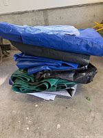 Stack of assorted coloured tarps folded on floor