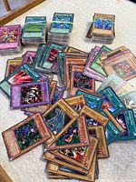 Stacks and spread of assorted Yu-Gi-Oh! cards on tabletop