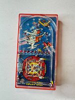 Front view of Bluebox Lucky Ball handheld pinball game showing playfield graphics and plunger