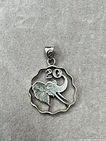 Front view of pendant showing elephant motif and “20”