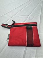 Front view of red Husky zip pouch showing zipper, mesh accent, strap