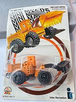 Front of sealed blister pack showing orange and black wheel loader