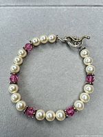 Full view of beaded bracelet laid flat showing pearls, pink beads, spacers and toggle clasp