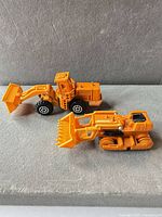 Both orange plastic construction toy vehicles side by side