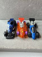 Front angled view of three Hot Wheels cars showing colors, engines, wheels