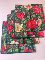 Stack of four floral poinsettia cloth napkins showing pattern and color