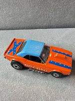 Left side view of orange Dodge Challenger diecast showing Revin' Rebel text, blue roof, side pipes
