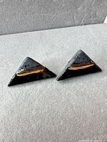 front view of both triangular earrings showing black glaze, grey ceramic and gold accent
