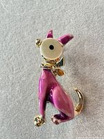Front view of purple enamel gold-tone dog brooch on neutral background