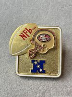 Front view of lapel pin showing helmet, football and NFC logo