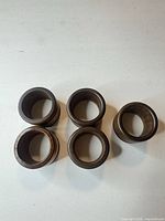 Five brown wooden napkin rings displayed top view