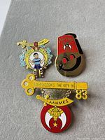 Front view of the three Shriners Aahmes enamel lapel pins on fabric background