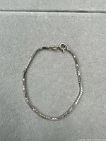 Full view of sterling silver box chain bracelet laid flat showing entire length and clasp