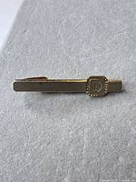 Full view of gold-tone Swank tie clip with monogram D bezel
