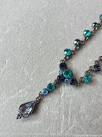 Necklace laid flat showing rhinestone colors, chain and pendant