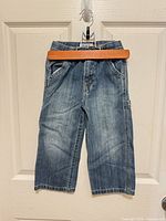 Front view of girls' light wash carpenter jeans on hanger