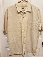 Front view of Tommy Bahama beige/cream silk camp shirt on hanger