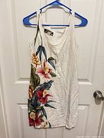 Front view of white sleeveless dress with floral print on hanger