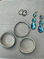 All five jewellery pieces laid out: three bracelets, one pair dangle earrings, one pair clip-on earrings