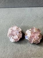 front view of both pink glass bead cluster clip-on earrings on grey surface