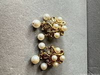 Both Trifari gold-tone clip-on earrings showing front design and dangling faux pearls