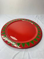Front view of red charger plate with green tree border