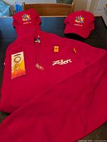 Group shot showing sweatshirt, two hats, packaged pin, dog tag necklace, loose pins