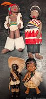 Four dolls laid out on black surface showing full view