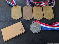 Front view of four rectangular Esso medals, one round medal and Texaco card holder