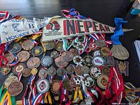 Pile of assorted medals with ribbons, Nepean pennant and Kanata-Carleton cloth piece visible
