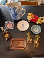 Overview showing pottery jug, cat bank, lobster shakers, four ashtrays and mini bottle