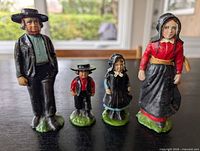 Front view of all four painted cast iron Amish figurines