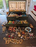 Open jewelry box showing exterior and assorted jewelry spread on table