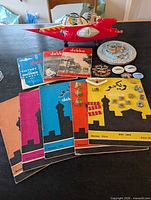 Overview of lot showing jet toy, Dekko magazines, Naval medallion, badges and pins