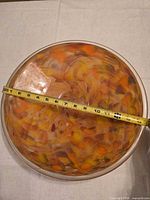 Top view of bowl showing diameter with tape measure and interior swirl colors