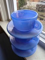 Stacked blue glass cups with saucers showing translucence and design