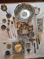 Entire lot laid out showing bowls, clock, vase, knives, corkscrew, candle snuffers, figurines