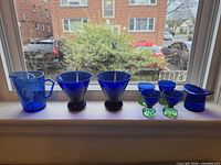 Full group of eight cobalt blue glass pieces on windowsill