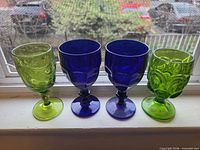 Four goblets lined up on windowsill showing colors and patterns
