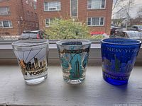 Front view of three shot glasses displaying skyline graphics and colors