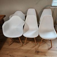 Front view of eight white molded shell chairs showing overall design and leg construction