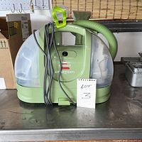 Front view of Bissell Little Green cleaner showing tanks, hose, nozzle