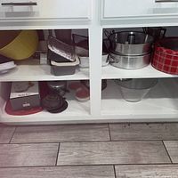 Cupboard shelves showing entire assortment of bowls, bakeware, teapot, potato ricer box