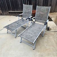 Two grey sling aluminum folding lounge chairs on patio