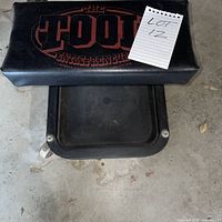 Top view showing padded seat with THE TOOL ENTREPRENEUR logo and note card